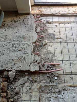 Foto von einem Fußboden, wo die Heizungsrohre und der Beton herausgestemmt werden.