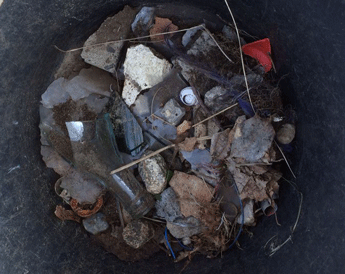Foto von einem Eimer, der mit Glasscherben und anderem Müll gefüllt ist - heute.